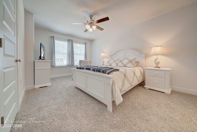 bedroom with ceiling fan, light colored carpet, and a textured ceiling