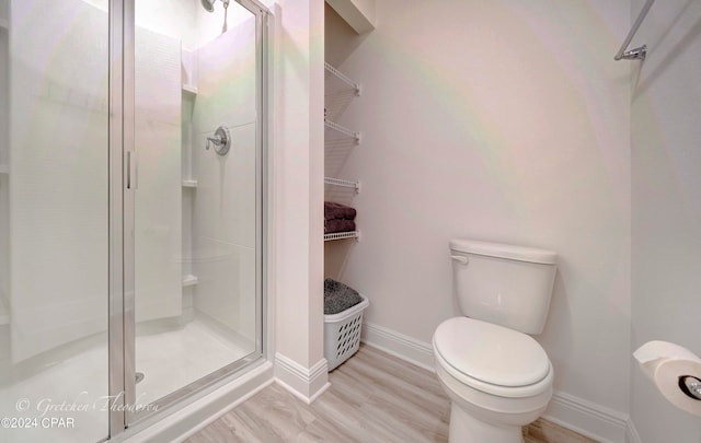 bathroom featuring toilet, a shower with door, and hardwood / wood-style floors