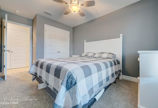 carpeted bedroom featuring ceiling fan and a textured ceiling