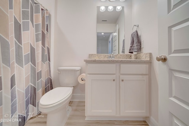 bathroom with walk in shower, hardwood / wood-style floors, vanity, and toilet