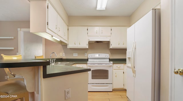 kitchen featuring white cabinets, white appliances, a textured ceiling, and light wood-type flooring