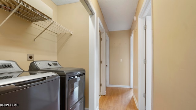 laundry area featuring washing machine and clothes dryer and light hardwood / wood-style flooring