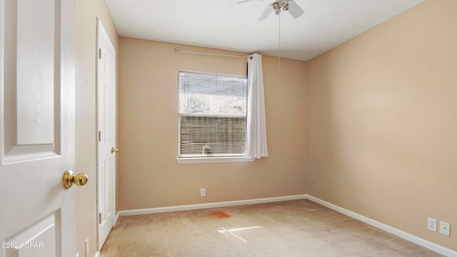 spare room with ceiling fan and light colored carpet