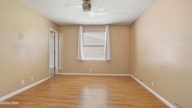 empty room with ceiling fan, a textured ceiling, and light wood-type flooring