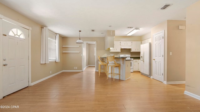 kitchen featuring white cabinets, white appliances, decorative light fixtures, a kitchen breakfast bar, and light hardwood / wood-style floors