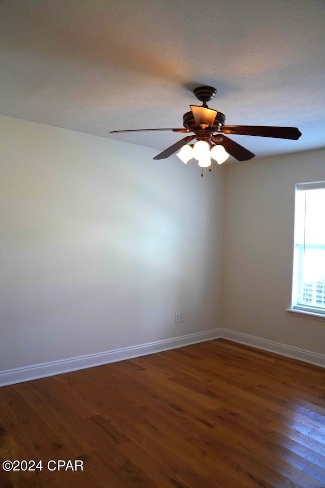 empty room with a textured ceiling, dark hardwood / wood-style floors, and ceiling fan