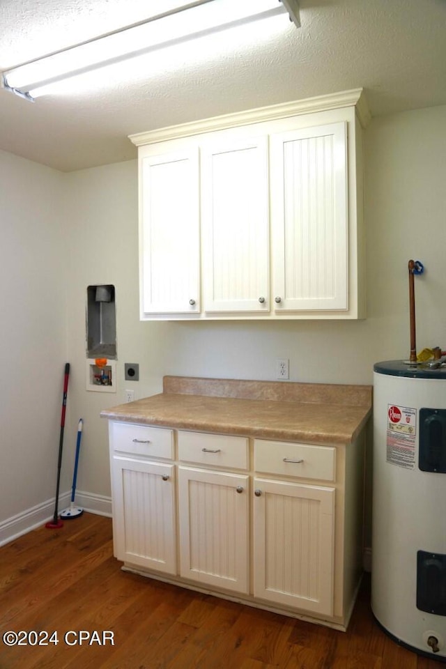 kitchen featuring hardwood / wood-style flooring, white cabinetry, and electric water heater