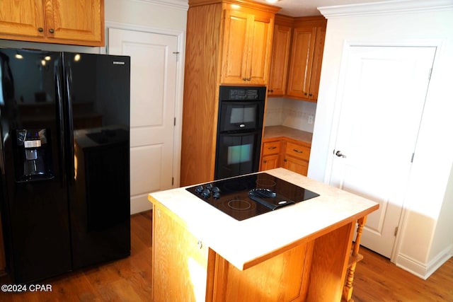 kitchen with ornamental molding, light wood-type flooring, decorative backsplash, and black appliances