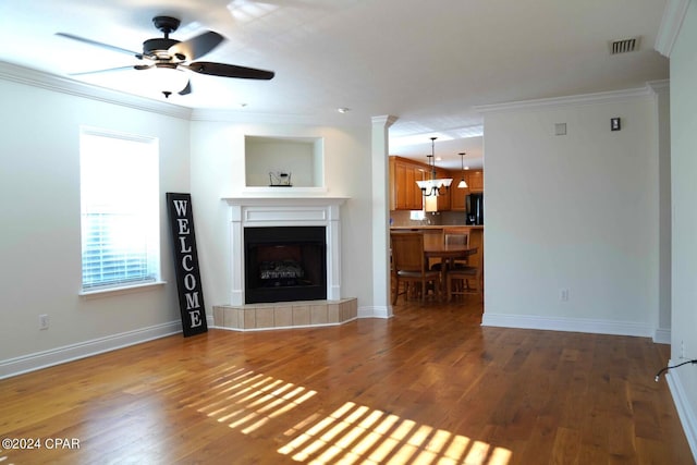 unfurnished living room with a fireplace, crown molding, dark wood-type flooring, and ceiling fan