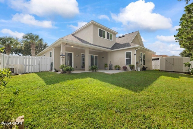 rear view of house with a storage shed, a lawn, and a patio area