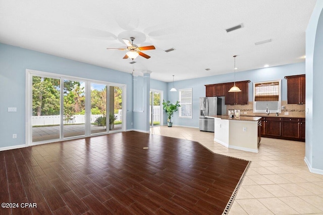 unfurnished living room with light hardwood / wood-style flooring, a textured ceiling, ceiling fan, and sink