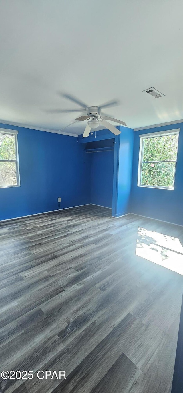 unfurnished room with ceiling fan, a wealth of natural light, and dark hardwood / wood-style flooring