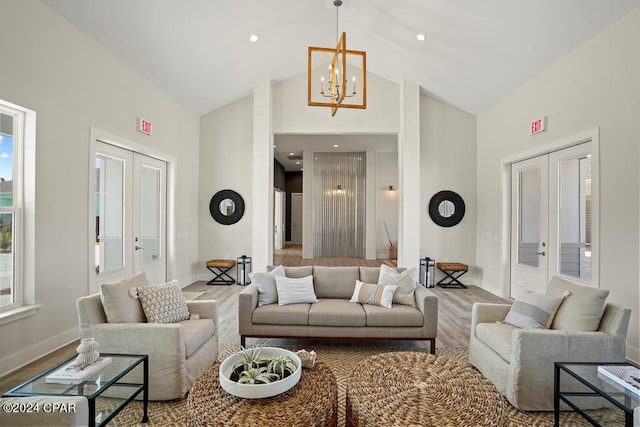 living room with hardwood / wood-style floors, an inviting chandelier, high vaulted ceiling, and french doors