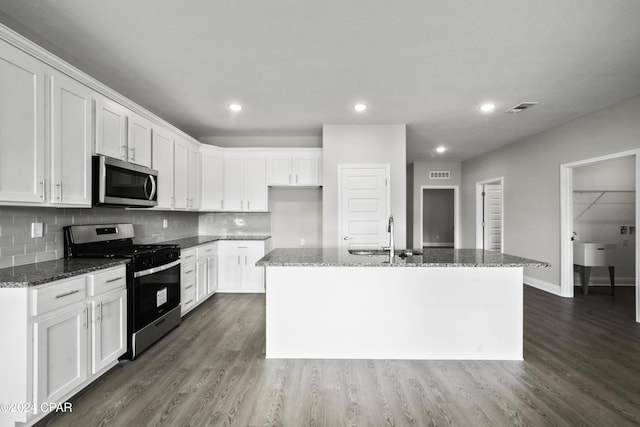 130 Canvas Ln Unit 69, Port St Joe, FL 32456 - kitchen featuring appliances with stainless steel finishes, dark wood-style flooring, white cabinets, a center island with sink, and dark stone counters