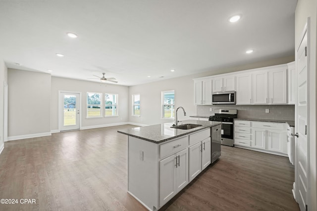 kitchen with dark stone counters, sink, appliances with stainless steel finishes, dark hardwood / wood-style flooring, and white cabinetry