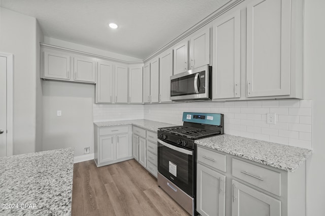 164 Canvas Ln Unit 72, Port St Joe, FL 32456 - kitchen with appliances with stainless steel finishes, light wood-style floors, light stone counters, backsplash, and a textured ceiling