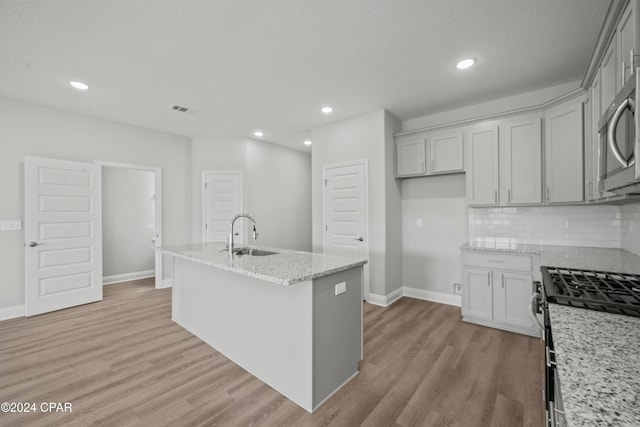 164 Canvas Ln Unit 72, Port St Joe, FL 32456 - kitchen with stainless steel appliances, light wood-style flooring, light stone countertops, tasteful backsplash, and a center island with sink