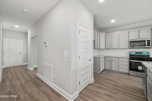 kitchen with gray cabinetry, hardwood / wood-style floors, and appliances with stainless steel finishes