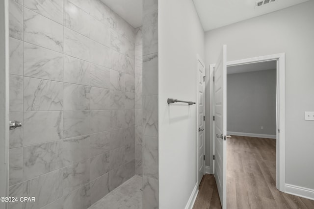 bathroom featuring wood-type flooring and tiled shower