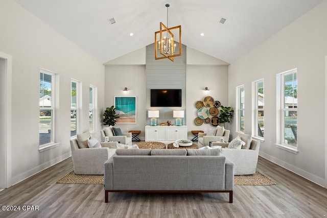 living room featuring a healthy amount of sunlight, light wood-type flooring, high vaulted ceiling, and an inviting chandelier