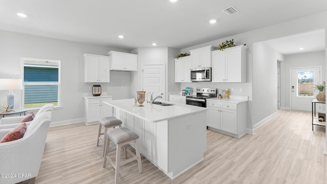 kitchen with visible vents, stainless steel dishwasher, open floor plan, white cabinets, and a sink