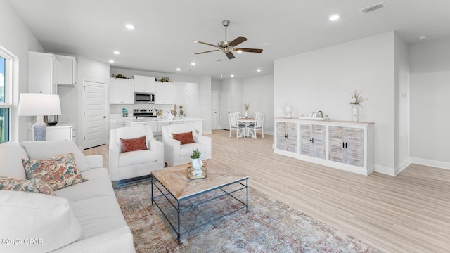 living room with baseboards, light wood-style floors, visible vents, and recessed lighting