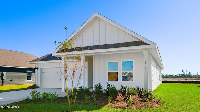 view of front of home with a shingled roof, concrete driveway, board and batten siding, a front yard, and a garage