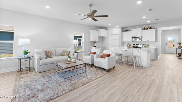 living room featuring light hardwood / wood-style flooring and ceiling fan