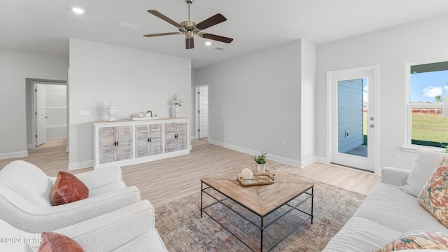 living room featuring light wood-style floors, visible vents, baseboards, and recessed lighting