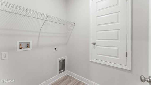 clothes washing area with washer hookup, light wood-style floors, electric dryer hookup, laundry area, and baseboards