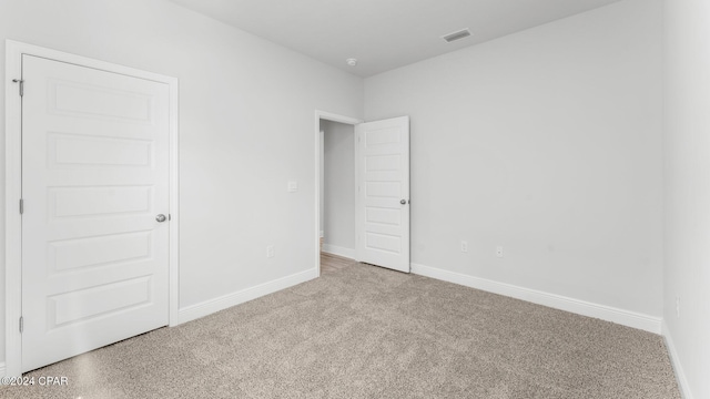 empty room with baseboards, visible vents, and carpet flooring