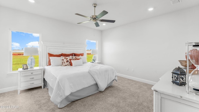 bedroom featuring multiple windows, ceiling fan, and light carpet