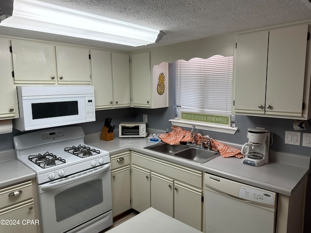 kitchen featuring a textured ceiling, sink, and white appliances