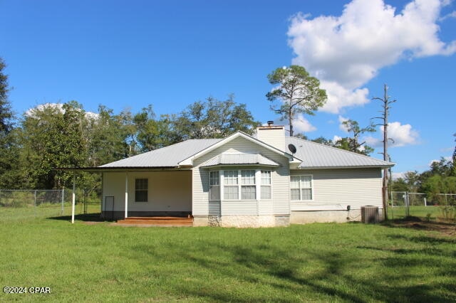 back of property featuring a lawn and central AC