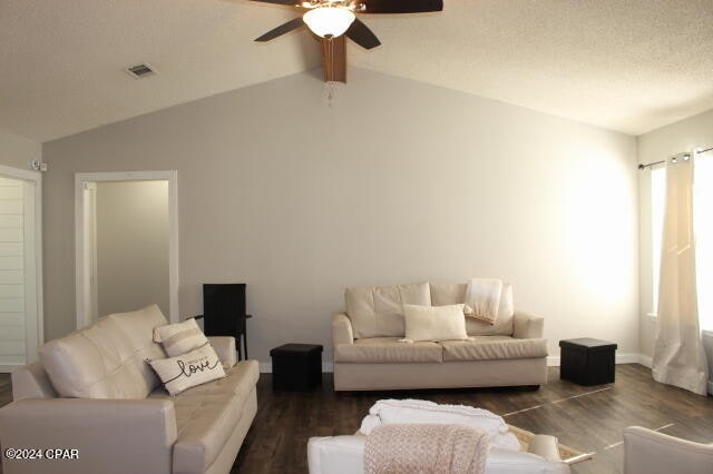 living room with ceiling fan, dark wood-type flooring, and vaulted ceiling