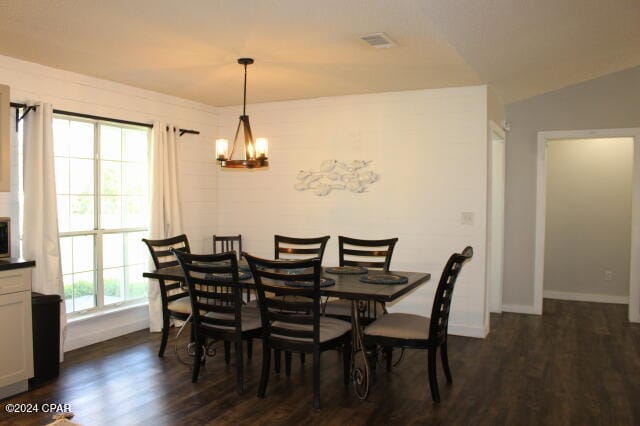 dining area with a notable chandelier, dark wood-type flooring, vaulted ceiling, and a healthy amount of sunlight