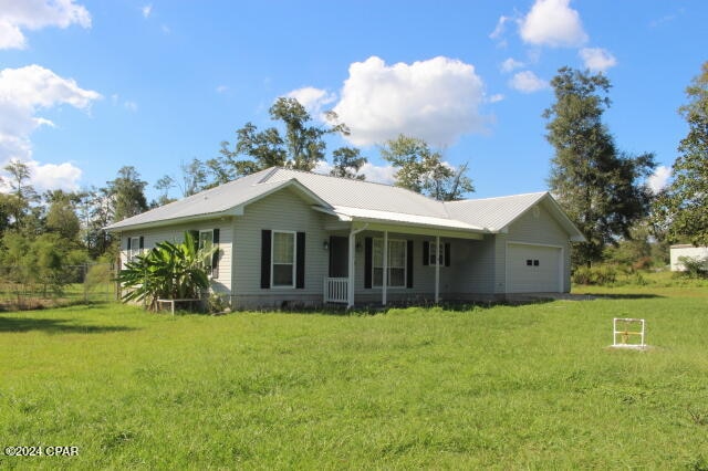 ranch-style home featuring a garage, a porch, and a front lawn