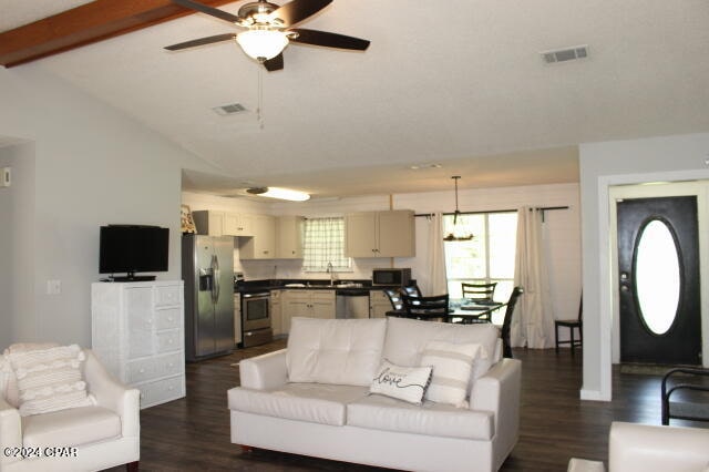 living room featuring vaulted ceiling with beams, ceiling fan, dark hardwood / wood-style floors, and sink