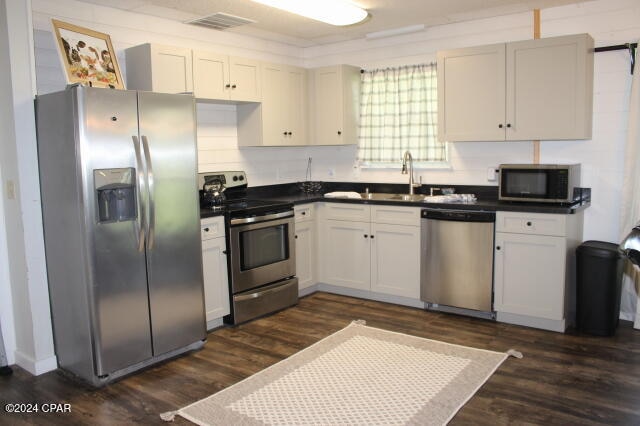 kitchen with appliances with stainless steel finishes, dark hardwood / wood-style floors, and white cabinets