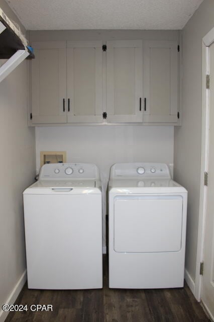 laundry area featuring cabinets, a textured ceiling, dark wood-type flooring, and washing machine and dryer