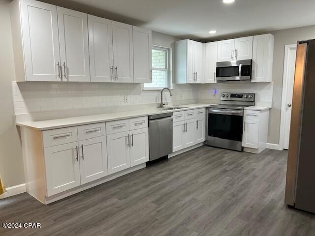 kitchen featuring decorative backsplash, dark hardwood / wood-style flooring, sink, stainless steel appliances, and white cabinetry