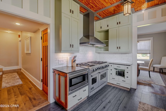 kitchen featuring backsplash, wall chimney range hood, stainless steel appliances, dark hardwood / wood-style floors, and green cabinets