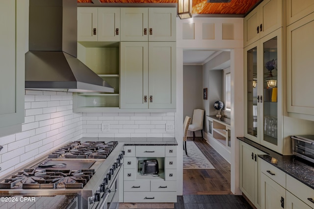 kitchen featuring tasteful backsplash, high end stove, range hood, dark stone counters, and dark hardwood / wood-style floors