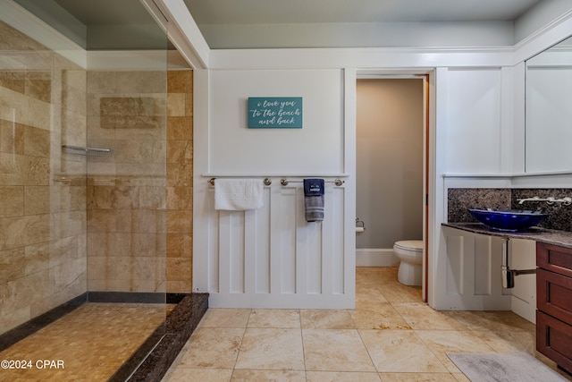 bathroom with tiled shower, vanity, and toilet