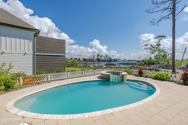 view of swimming pool featuring a water view, an in ground hot tub, and a patio area