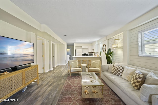 living room featuring a textured ceiling, dark wood-type flooring, and wooden walls