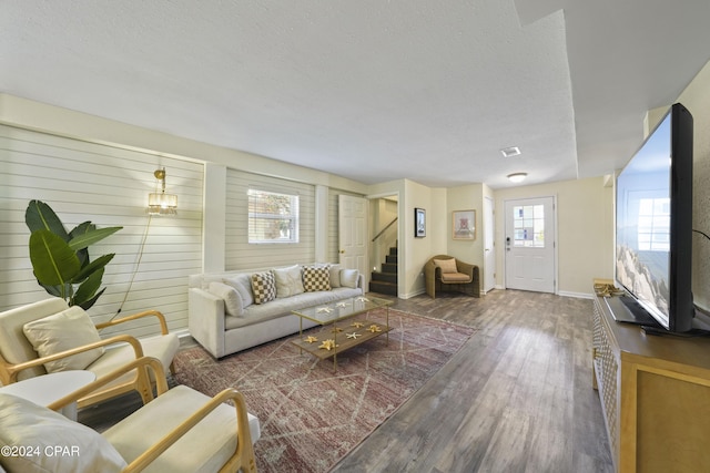 living room with a textured ceiling, dark hardwood / wood-style floors, and wood walls