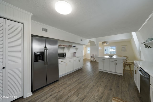 kitchen with appliances with stainless steel finishes, white cabinetry, dark wood-type flooring, and crown molding