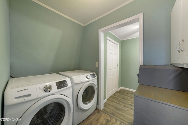 washroom featuring washing machine and clothes dryer, crown molding, and wood-type flooring