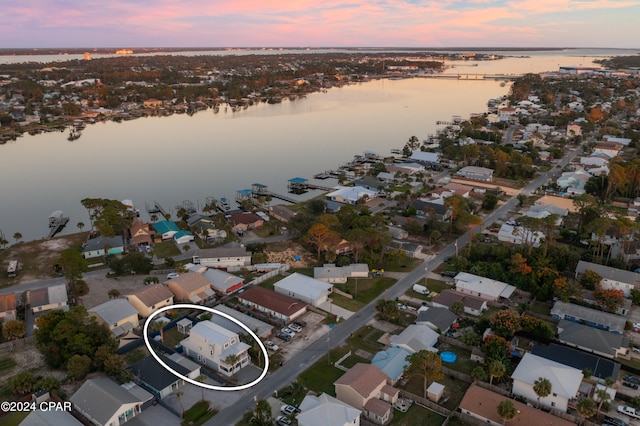 aerial view at dusk featuring a water view